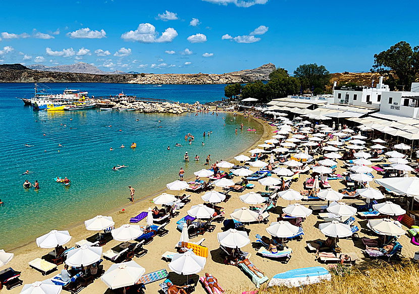 Solsängar och parasoll på stränderna i Lindos på Rhodos. 