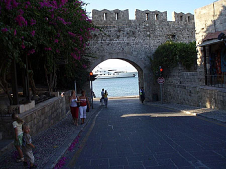 En av portarna i gamla stan och med en yacht fångad på väg ut ur hamnen. Rhodos.